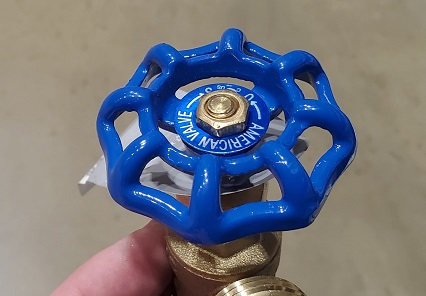 Photo of round wheel handle garden hose faucet.